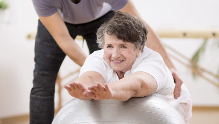 Nuestro Blog 58 Mujer madura haciendo pilates con ayuda de su entrenador.